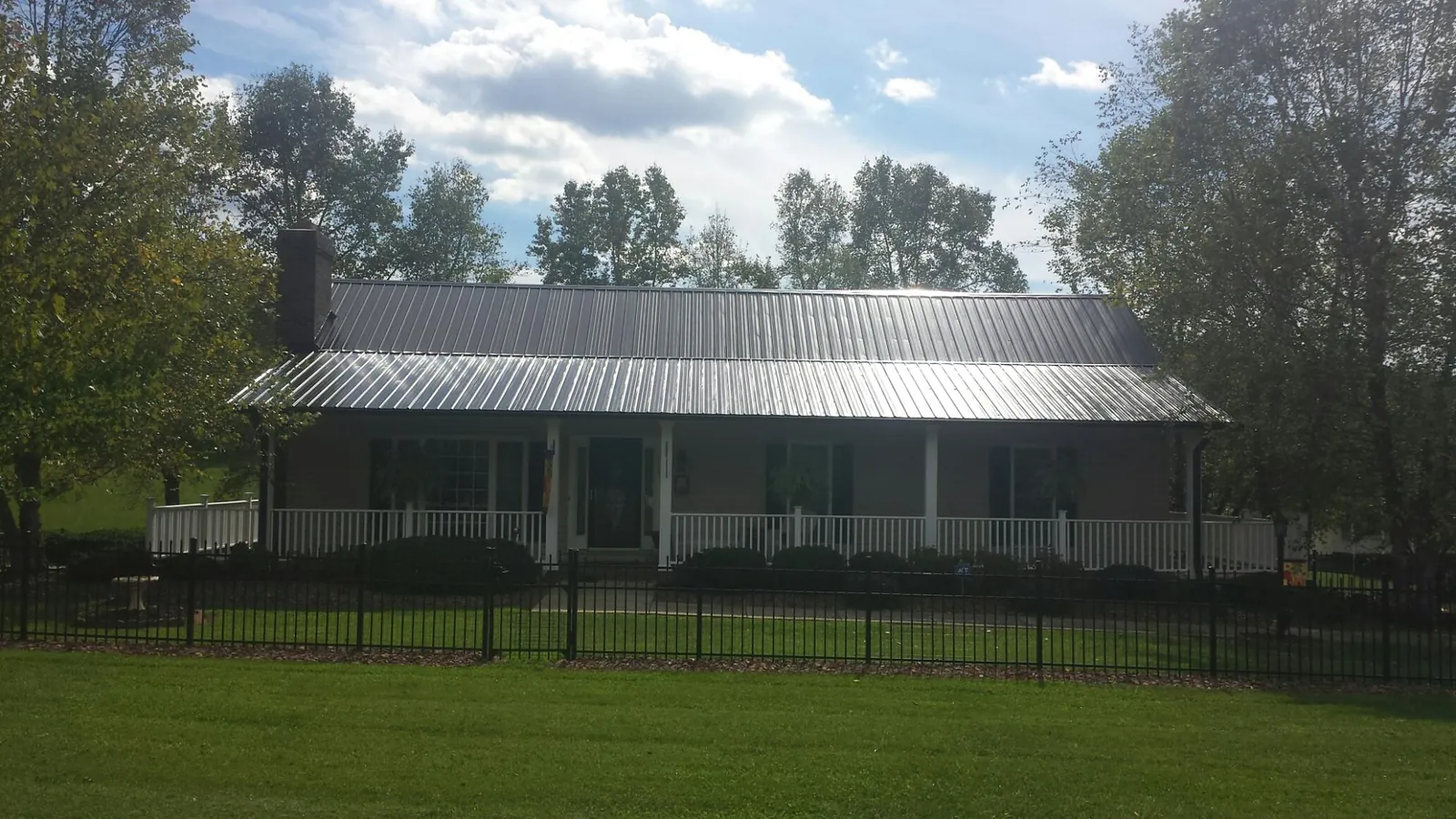Gray metal roof on a brick ranch with a full width front porch — Gutter Guard Installation work by our crew in Arvada