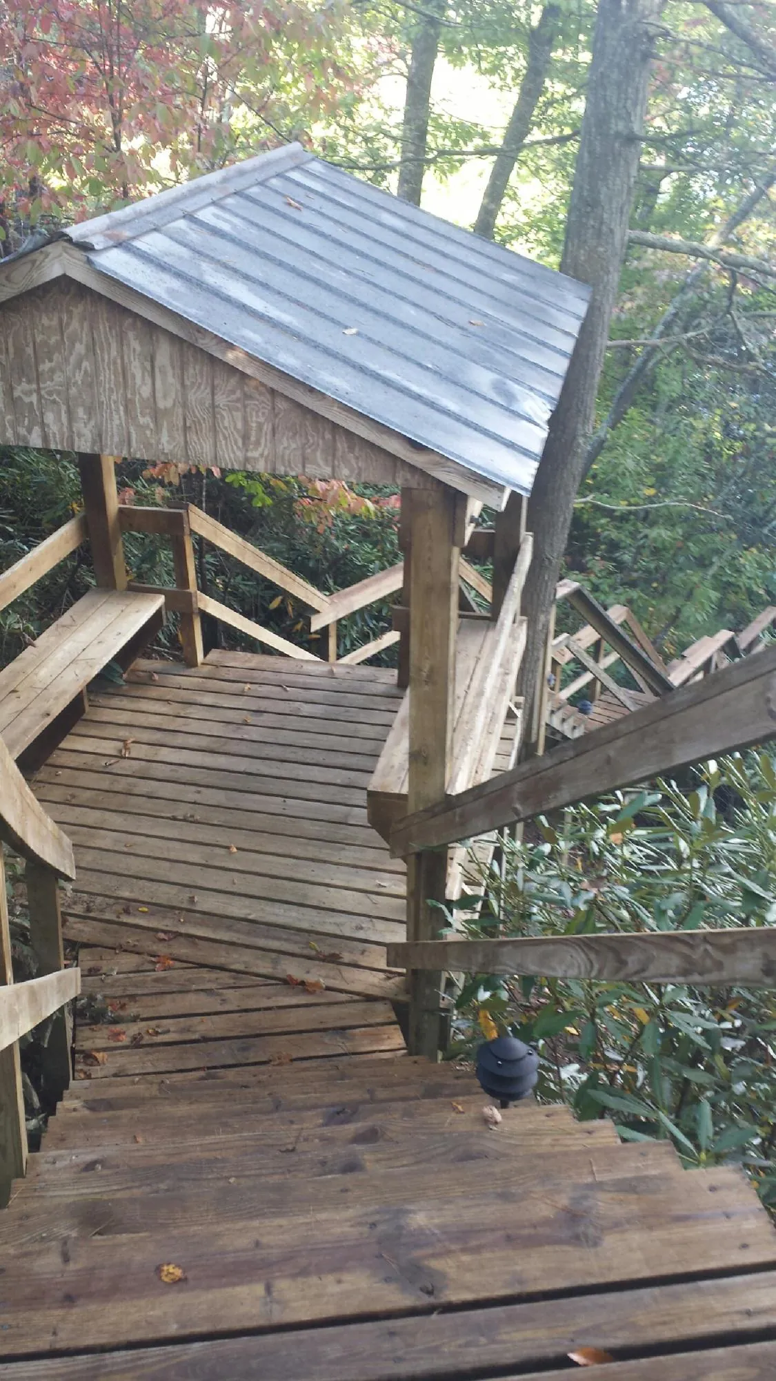 Metal roofed shelter over wooden steps on a wooded walkway — Skylight Repair & Installation work by our crew in Arvada