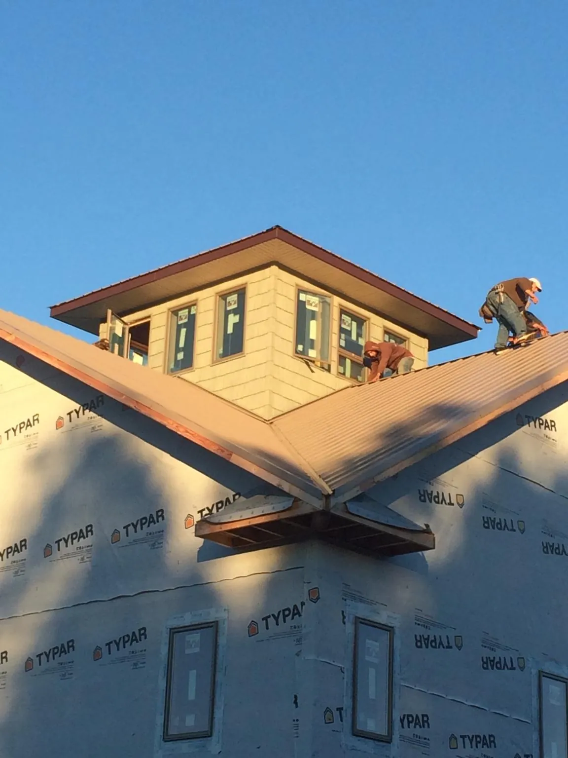 Roofers working around a rooftop cupola on a new metal roof at sunset — Roof Waterproofing in Arvada by Roofing Brothers